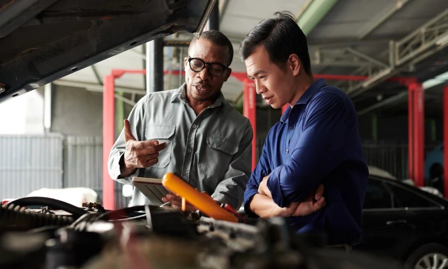 Car mechanic talking to owner, showing him results of diagnostic